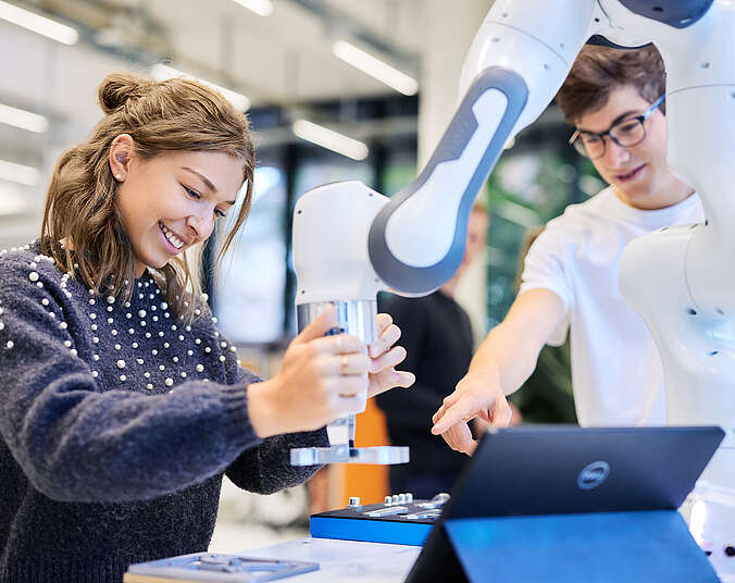 Jugendliche arbeiten am Roboterarm